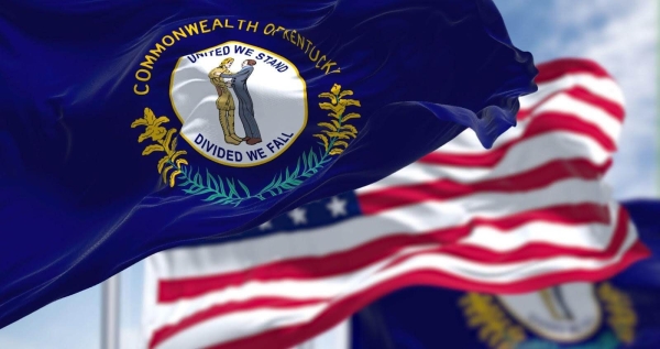 a state of kentucky flag waving along with the national flag of the united states in the background