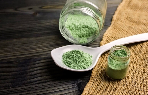 kratom powder in ceramic spoon and glass jars