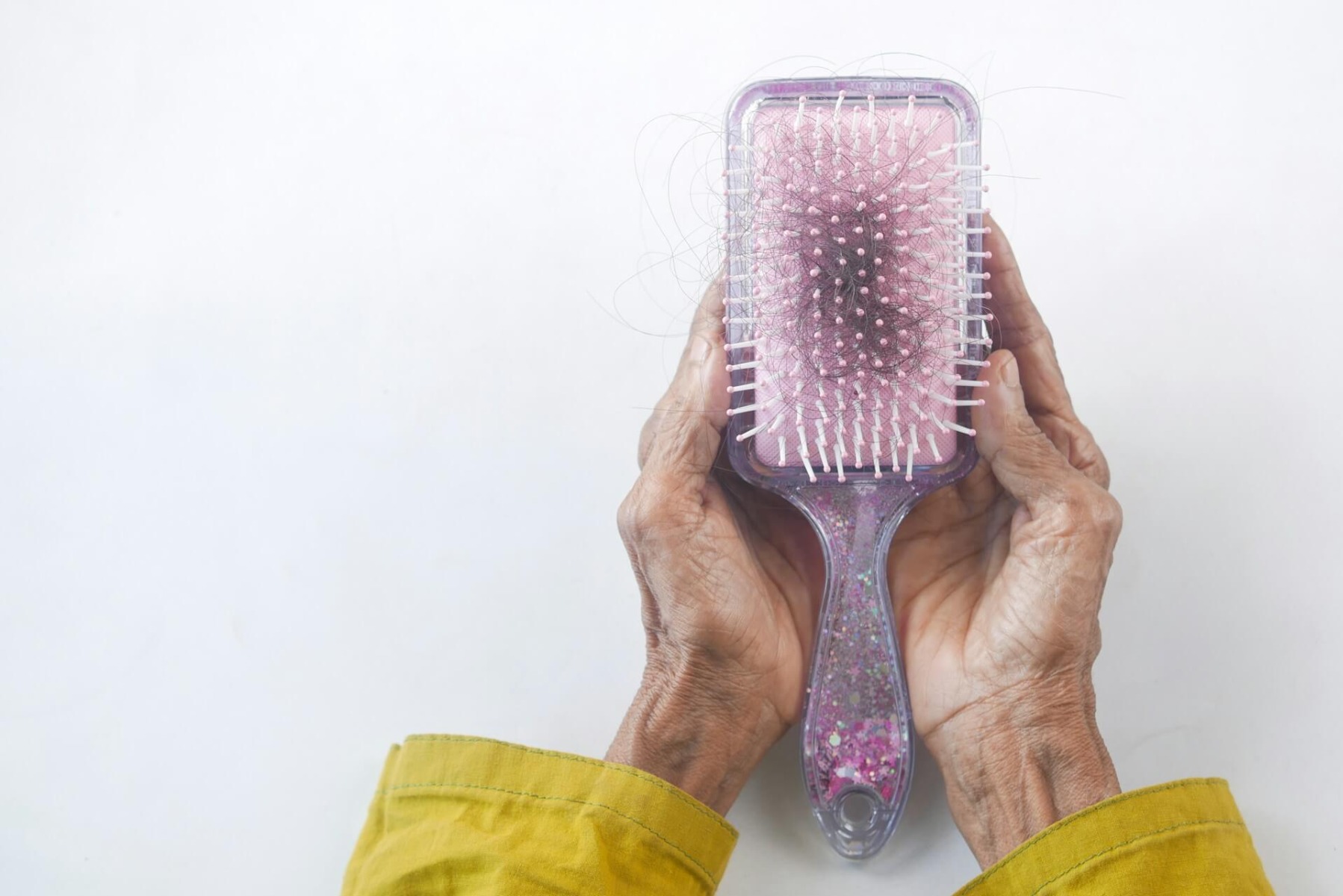 Old person’s hands holding a brush with hair in it